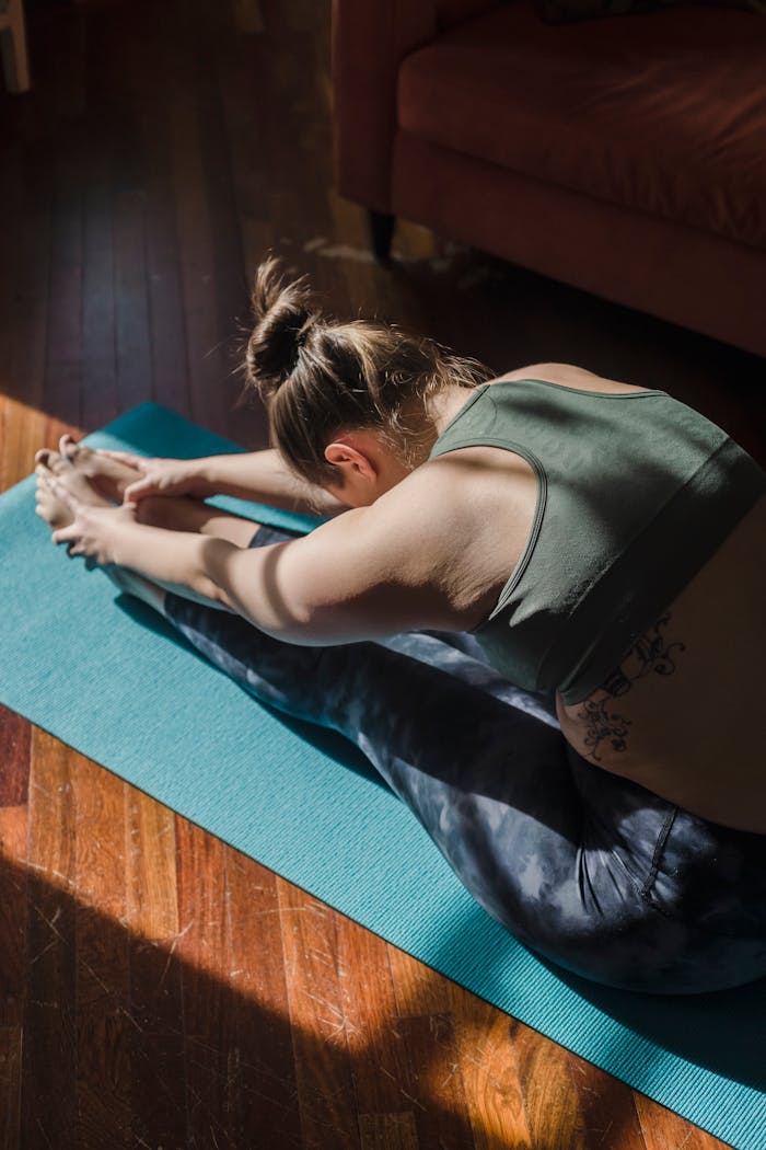 menu-02 Adult woman performing a yoga stretch on a mat in a cozy home setting, showcasing fitness and flexibility.