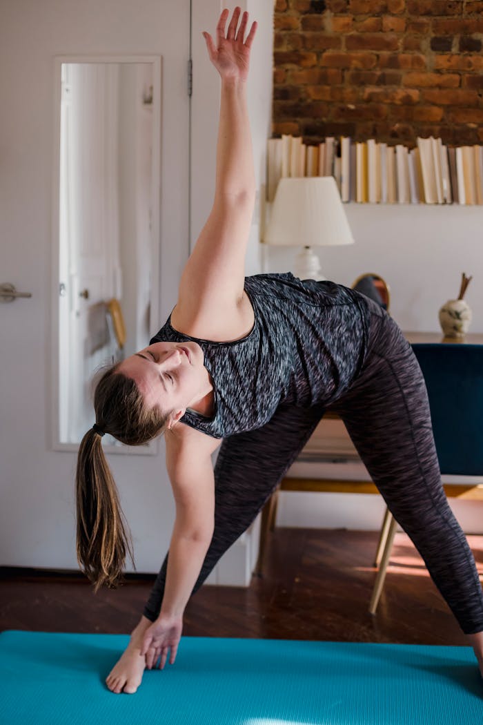 Woman performing yoga pose on a mat in a comfortable home environment, focusing on wellness.