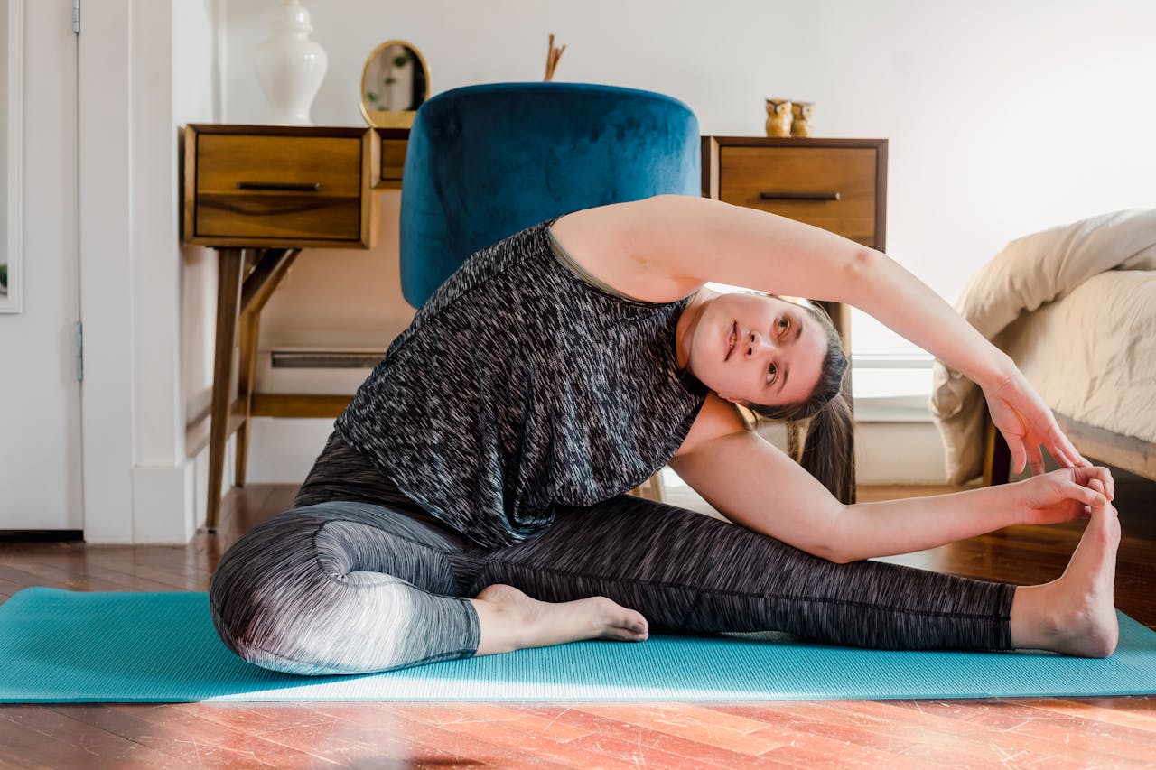 A woman stretches on a yoga mat at home, creating a calming yoga pose indoors.
