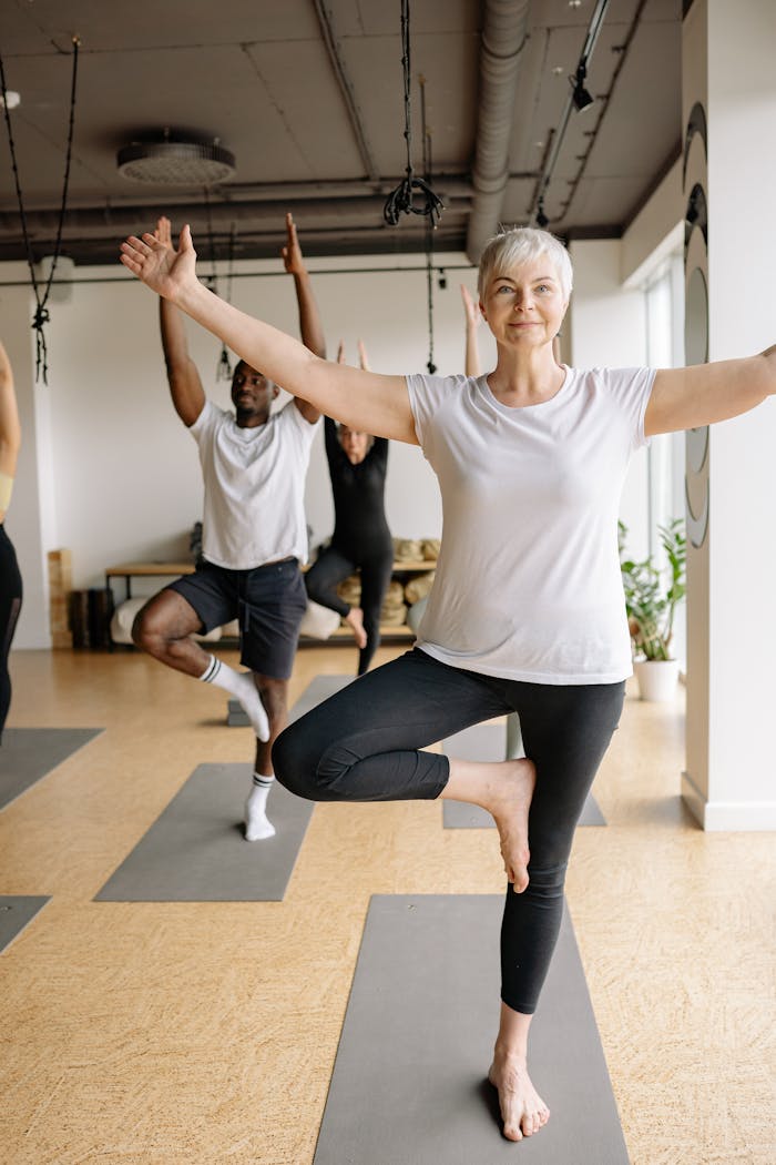 menu-04 Elderly woman practicing yoga in a calm studio setting, focusing on balance and well-being.